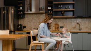 Parent feeding a baby in a high chair at home