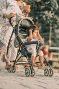 Parent walking outdoors with a child in a lightweight stroller