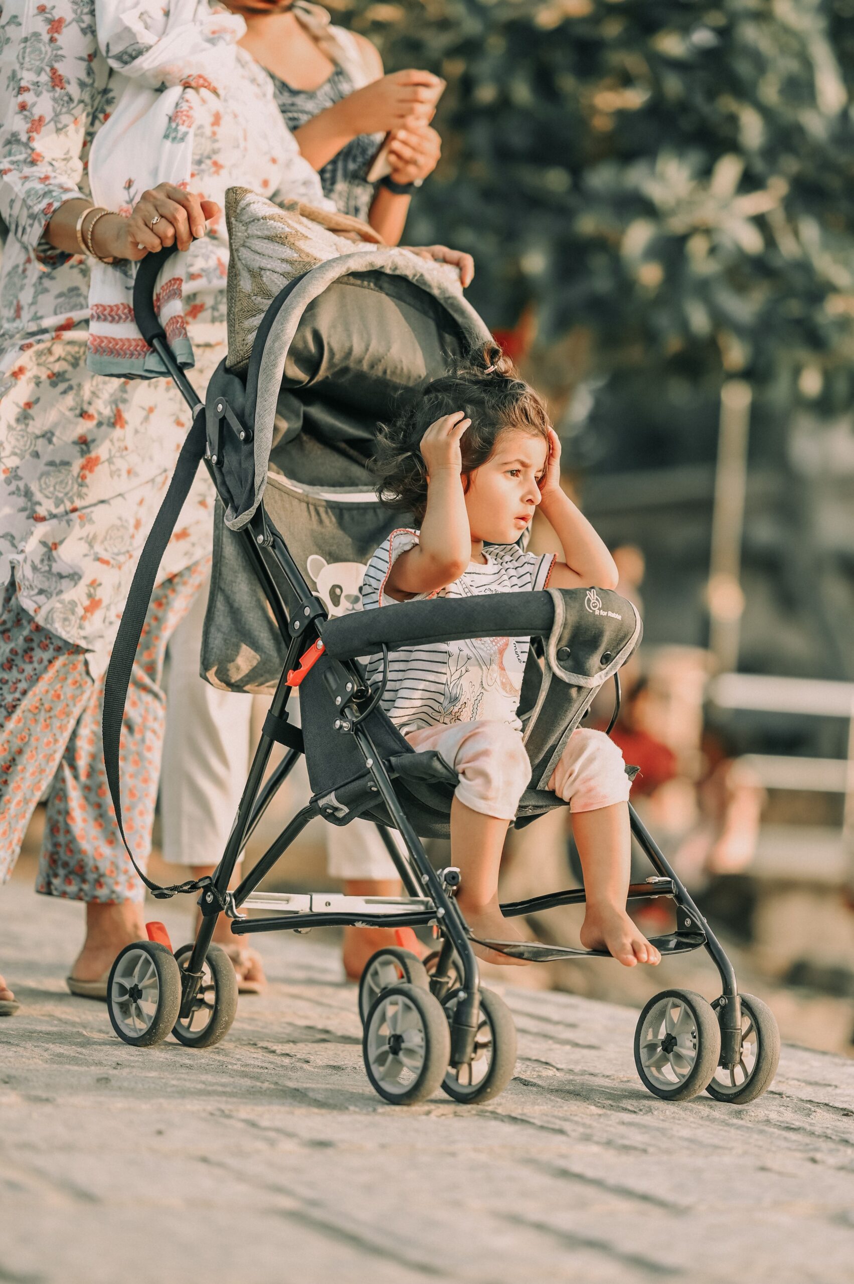Parent walking outdoors with a child in a lightweight stroller