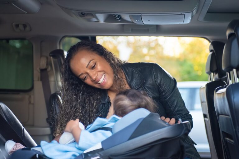 Mother looking at her baby in a car seat inside a vehicle