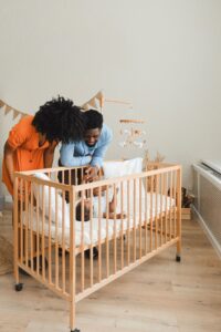 Parents standing beside their baby in a cot in a warm nursery