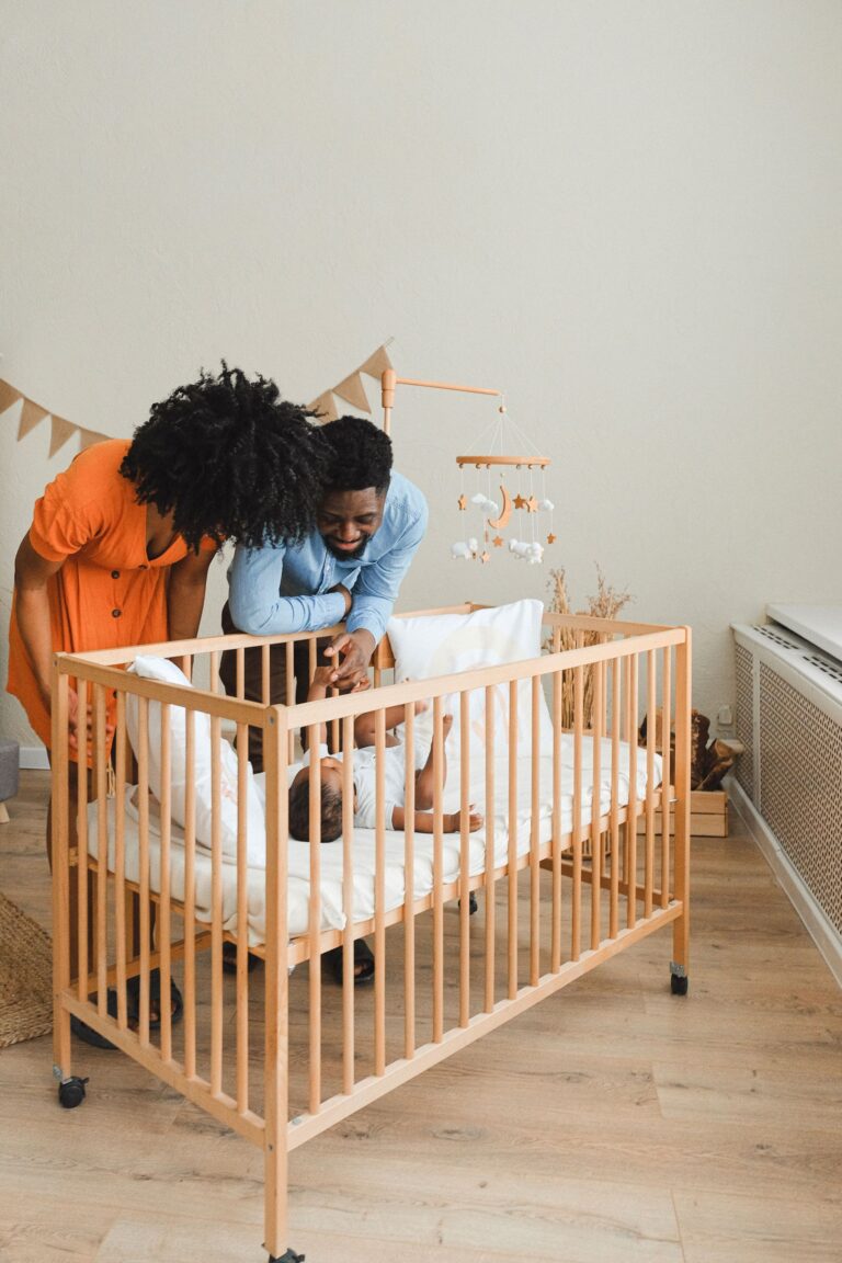 Parents standing beside their baby in a cot in a warm nursery