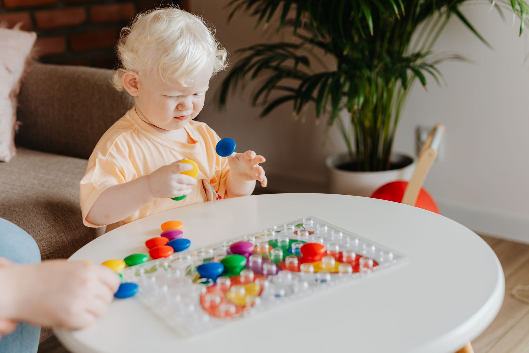 Toddler playing with colourful toys at a table at home