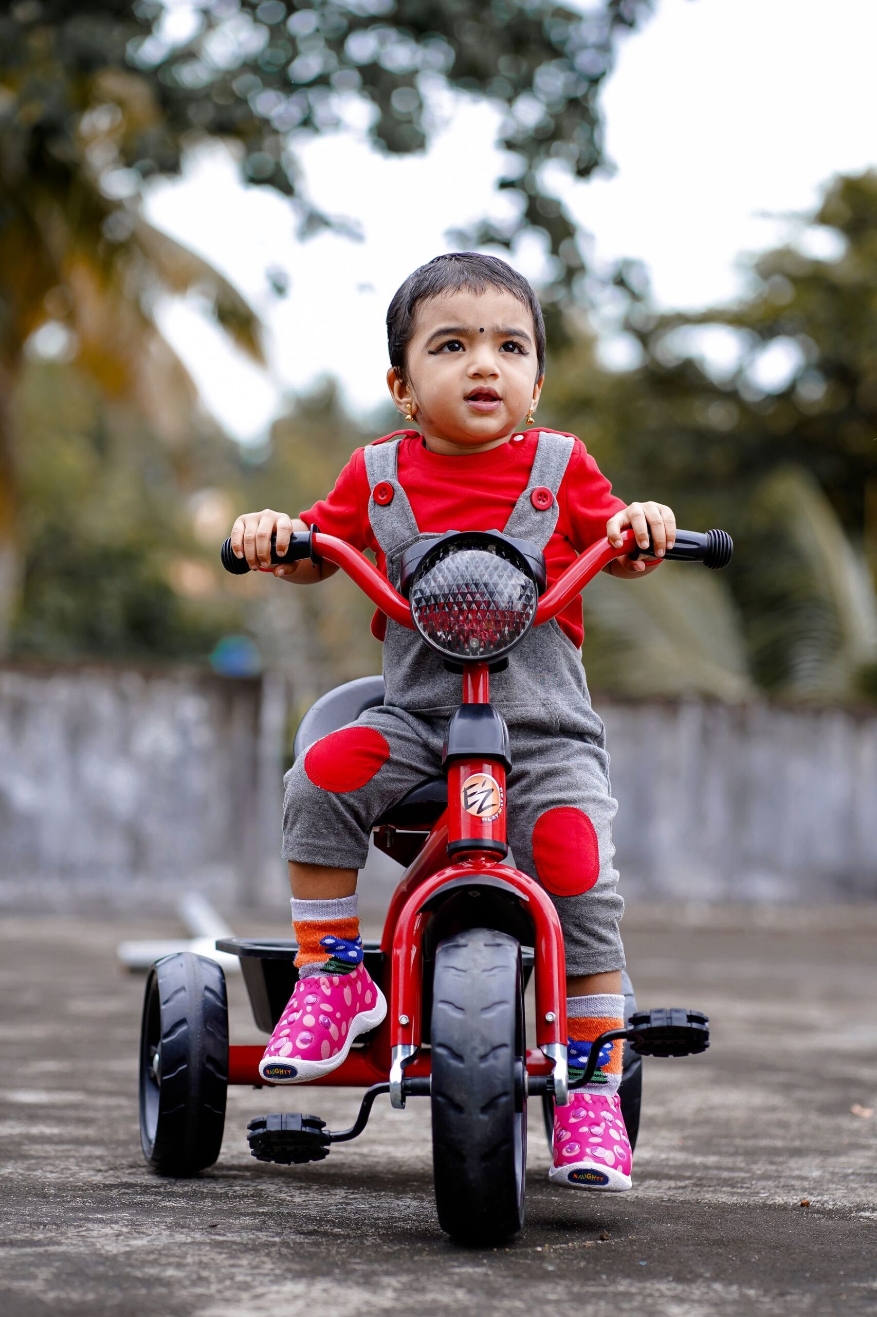 Child sitting on a red tricycle outdoors